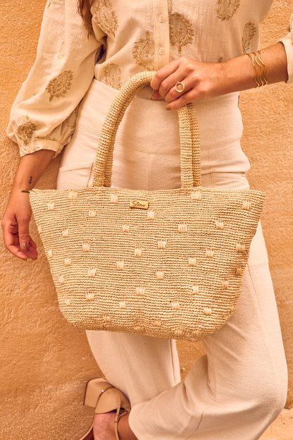 Mulher segurando a bolsa 'Gota', demonstrando o tamanho ideal para uso diário e combinando com um estilo em ambiente urbano.