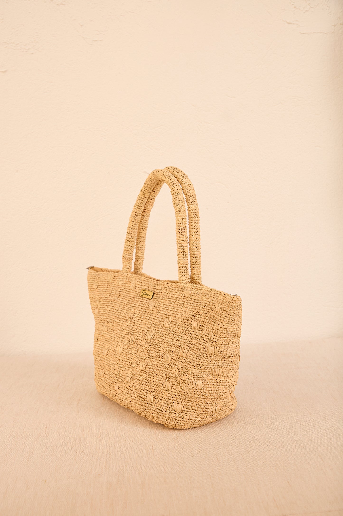 Close do trançado artesanal da bolsa 'Gota', mostrando a textura da palha resistente e o acabamento manual em tons neutros