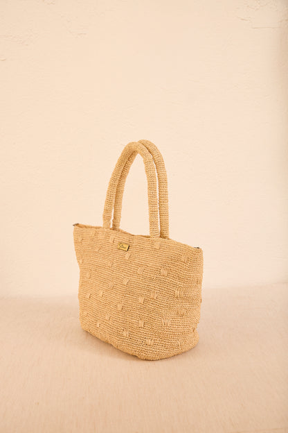 Close do trançado artesanal da bolsa 'Gota', mostrando a textura da palha resistente e o acabamento manual em tons neutros